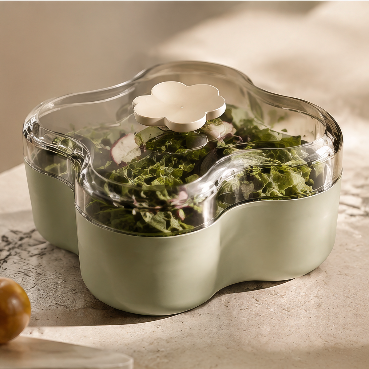 Sage-green flower-shaped food storage box with clear lid and floral handle, holding salad